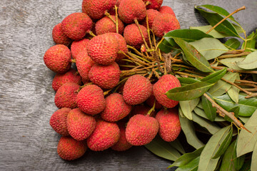 Organic juicy lychee with leaves closeup on a wooden table.