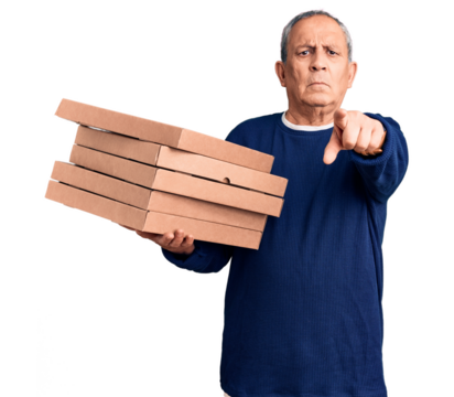 Senior handsome man holding pizza boxes pointing with finger to the camera and to you, confident gesture looking serious