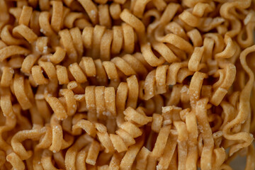 dried Instant noodles on white mulberry paper background. Instant noodles and pasta are wheat flour products call junk convenience food. Chinese and Japanese oriental noodle.