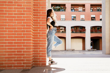 Fashion young adult woman model standing against on the brick wall outdoors