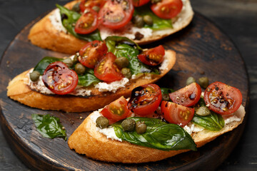 Traditional italian bruschetta with cherry tomatoes, cream cheese, basil leaves, capers and...