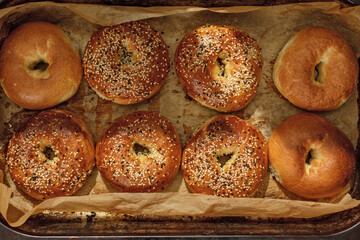 Full frame background of freshly made bagels on baking paper. Fresh and crispy bagels with sesame seeds. Jewish food concept.