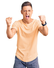 Young handsome man wearing casual clothes angry and mad raising fists frustrated and furious while...