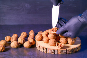 Chef peeling walnuts with a knife in the kitchen at the table