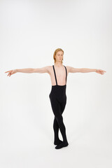 Young Athletic professional ballet dancer in a perfect shape performing over the white background. Legs in the fifth position, arms in second.