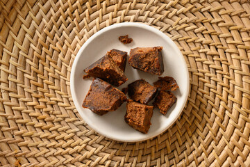 Kithul jaggery and treacle natural sweetener of palm in white bowl on traditional wicker tray. View...