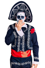 Young man wearing day of the dead costume over background bored yawning tired covering mouth with hand. restless and sleepiness.