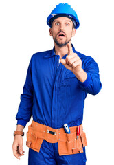 Young handsome man wearing worker uniform and hardhat pointing displeased and frustrated to the camera, angry and furious with you