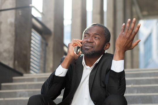Losing the case in court. Upset scared black man sitting on steps outside courthouse. Talking on the phone. Divorce, alimony, custody, bankruptcy, deportation.