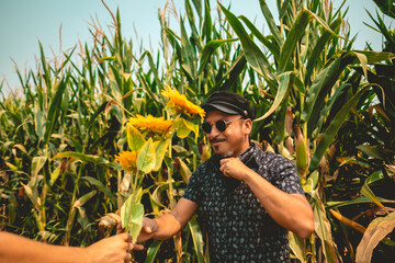 Rock and roll embraces nature: young rocker enjoys sunny day in a corn field with bouquet of...