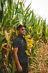Rock and roll embraces nature: young rocker enjoys sunny day in a corn field with bouquet of...