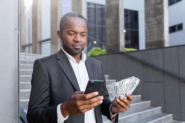 Portrait of confident African American male investor, businessman holding cash money in hand and...