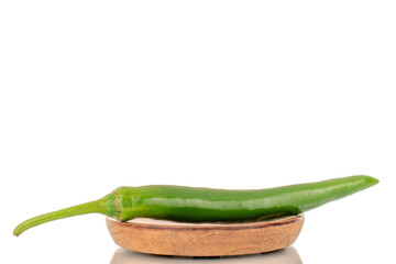 One green hot pepper on a wooden plate, a macro, isolated on a white background.
