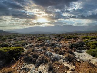greek landscape on island crete with mountain range and country side, clouds and sun.