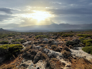 greek landscape on island crete with mountain range and country side, clouds and sun.