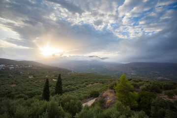 greek landscape on island crete with mountain range and country side, clouds and sundown.