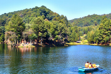 Fototapeta na wymiar lake in forest at sunny day, boat on the water with people, dam of the llano, villa del carbon state of mexico 