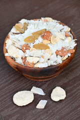 closeup the mix snack food drilled rice coconut,raisins,peanut ,sesame seeds in the wooden bowl on the brown background.