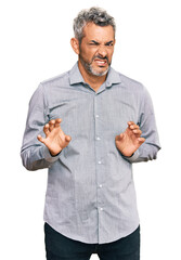 Middle age grey-haired man wearing casual clothes disgusted expression, displeased and fearful doing disgust face because aversion reaction. with hands raised