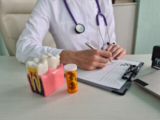 Female dentist works on dental implant and writes prescription for dental pills