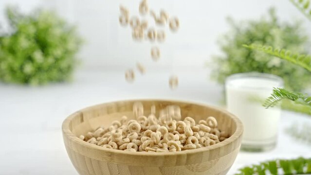 Circle shaped whole grain cereal falling into wooden bowl