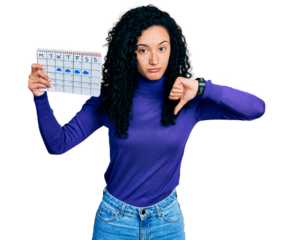 Young hispanic woman with curly hair holding rainy weather calendar with angry face, negative sign showing dislike with thumbs down, rejection concept