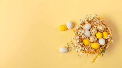 Easter candy chocolate eggs and almond sweets lying in a bird's nest decorated with flowers and...