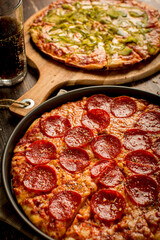 Pepperoni pizza and green pepper pizza on wood table