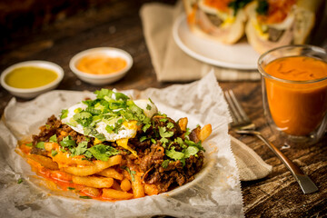 Vietnamese food - Kimchi fries with beef and egg and ham headcheese BBQ pork sandwich, and thai iced tea on the wooden table