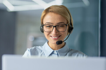 Young female office worker close up, businesswoman with headset phone for video call talking to...