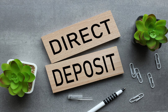 direct deposit two wooden blocks on a gray background. text on wood. Business concept image