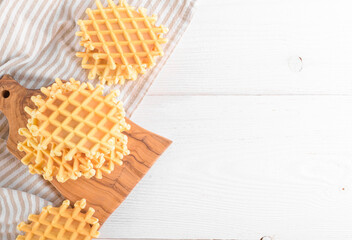 Ferratelle or pizzelle a traditional dessert or cookies on a cutting board with napkin on white wooden background, copy space, top view. Regional cuisine of Abruzzo, Italy. Like the well-known waffle
