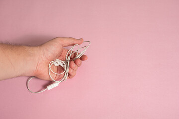 Mano sosteniendo manos libres en fondo rosado - Hand holding handsfree on pink background
