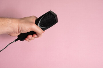Mano sosteniendo micrófono en fondo rosado - Hand holding microphone on pink background