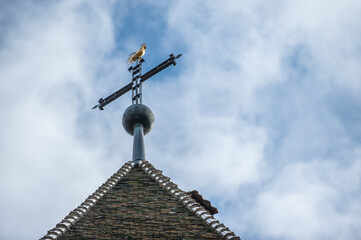 Fototapeta na wymiar Schindeldach mit Wetterhahn auf Kreuz und Wolkenhimmel