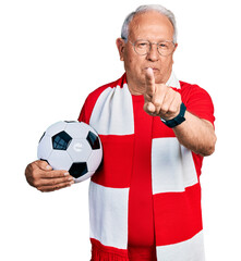 Senior man with grey hair football hooligan holding ball pointing with finger up and angry...