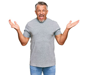 Naklejka premium Middle age grey-haired man wearing casual clothes celebrating victory with happy smile and winner expression with raised hands
