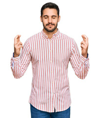 Young hispanic man wearing business shirt gesturing finger crossed smiling with hope and eyes closed. luck and superstitious concept.