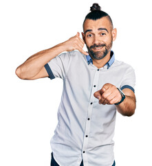 Hispanic man with ponytail wearing casual white shirt smiling doing talking on the telephone...