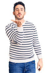 Young hispanic man wearing casual clothes looking at the camera blowing a kiss with hand on air being lovely and sexy. love expression.