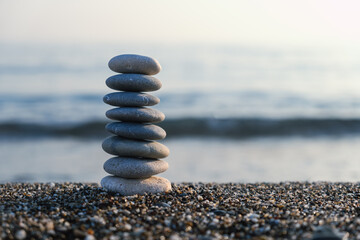 Balanced pebble pyramid silhouette on the beach with the ocean in the background. Zen stones on the...