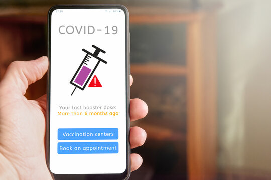 Man Holding Mobile Phone With Covid-19 Vaccine Report, App Interface Saying That His Last Booster Dose Was More Than 6 Months Ago, With Buttons To See Vaccination Centers And To Schedule Appointment