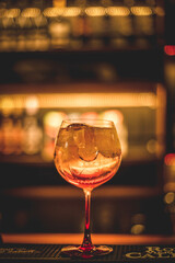 Hermoso trago de autor, variación de ramazzotti sabor naranja , posado en la barra de un bartender, al interior de un bar. Con el fondo desenfocado y tonos cálidos