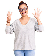 Young latin woman wearing casual clothes showing and pointing up with fingers number nine while...