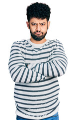 Young arab man with beard wearing casual striped sweater skeptic and nervous, disapproving expression on face with crossed arms. negative person.