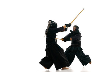 Two men, professional kendo athletes in uniform with helmet training with bamboo shinai sword...