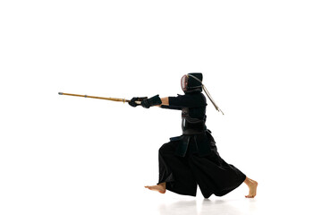 Strength. Man, professional kendo athlete in black uniform with sword, shinai training against white studio background. Concept of martial arts, sport, Japanese culture, action and motion