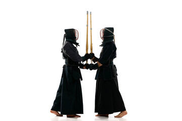 Full-length image of two men, professional kendo fighter, athletes in black uniform training...