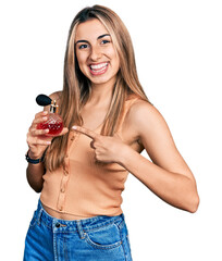 Hispanic young woman holding perfume smiling happy pointing with hand and finger