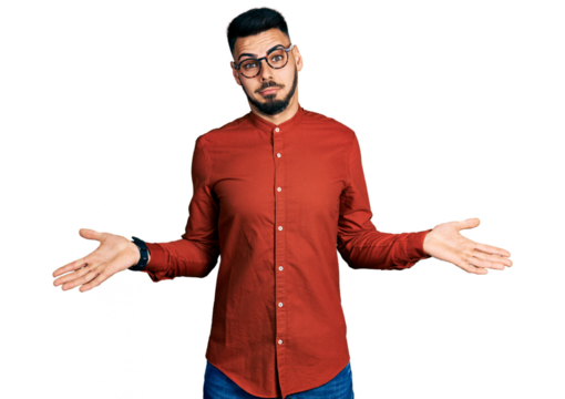 Young hispanic man with beard wearing business shirt and glasses clueless and confused expression with arms and hands raised. doubt concept.